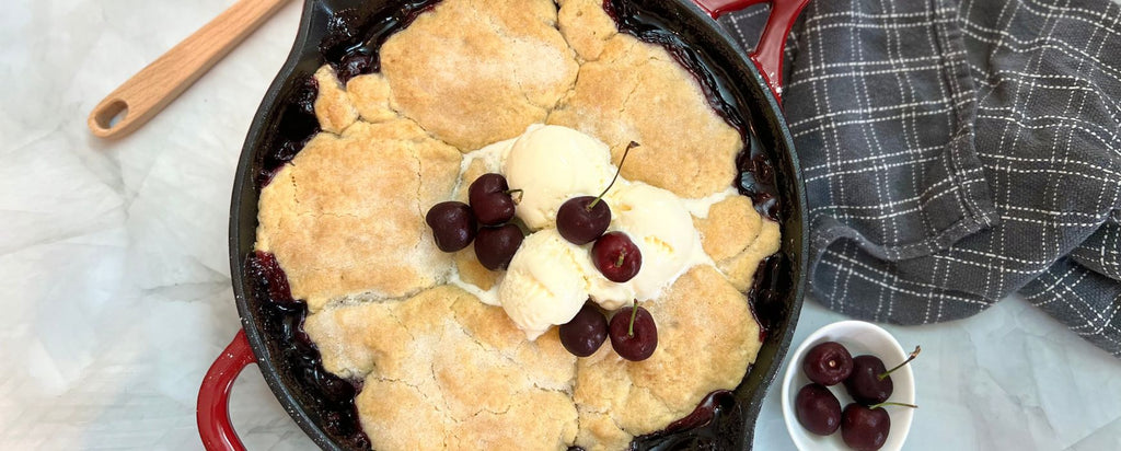 Cherry Cobbler topped with ice cream in a red skillet