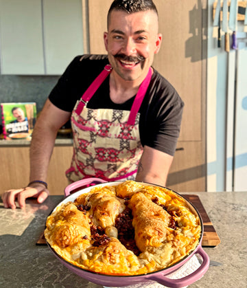 Joe Sasto holding a dish of food in a kitchen setting