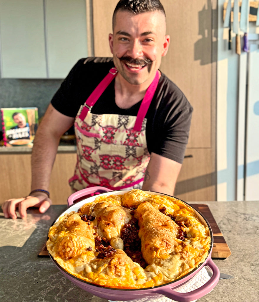 Joe Sasto holding a dish of food in a kitchen setting