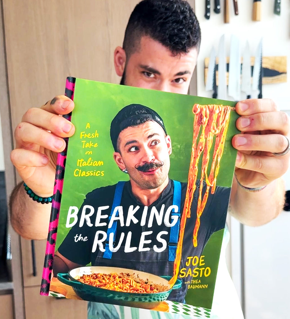 Joe Sasto holding a book titled 'Breaking the Rules' by Joe Sasto with a green cover.